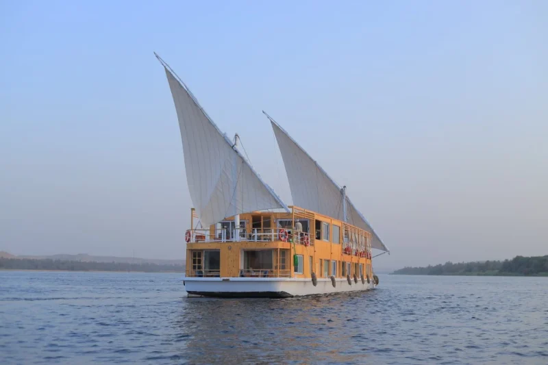 A traditional Egyptian sailboat navigating the river on a 4 nights Dahabiya Nile cruise from Esna to Aswan.