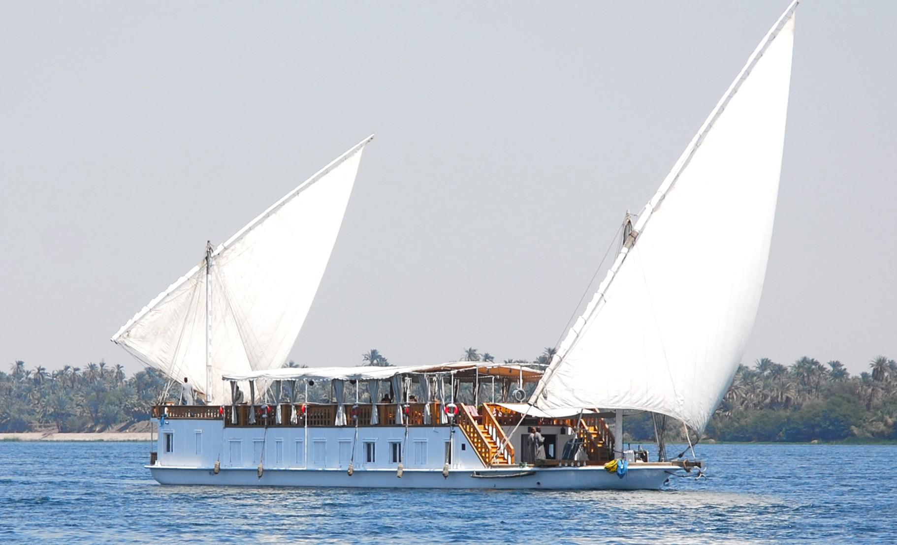 Traditional Dahabiya sailing boat cruising along the Nile River in Egypt, offering a calm and intimate travel experience.