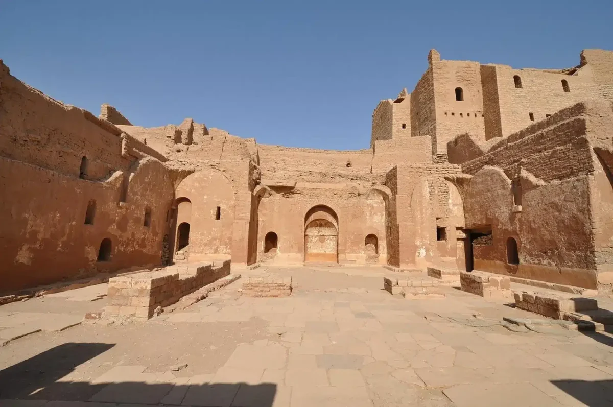 A traditional camel ride across the golden Aswan desert dunes toward the ancient ruins of St. Simeon Monastery with MSM Travel Egypt.
