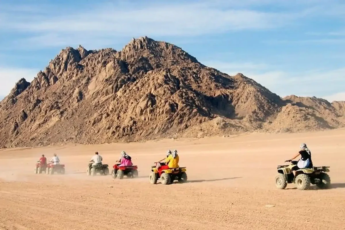 Tourists quad biking and riding camels in the Sharm El Sheikh desert before a Bedouin dinner show.