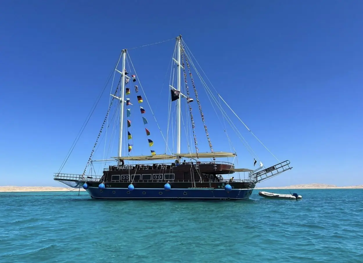 Guests relaxing on the wooden deck of the Pirates Premier Sailing Boat in Sharm El Sheikh during a luxury sea cruise.