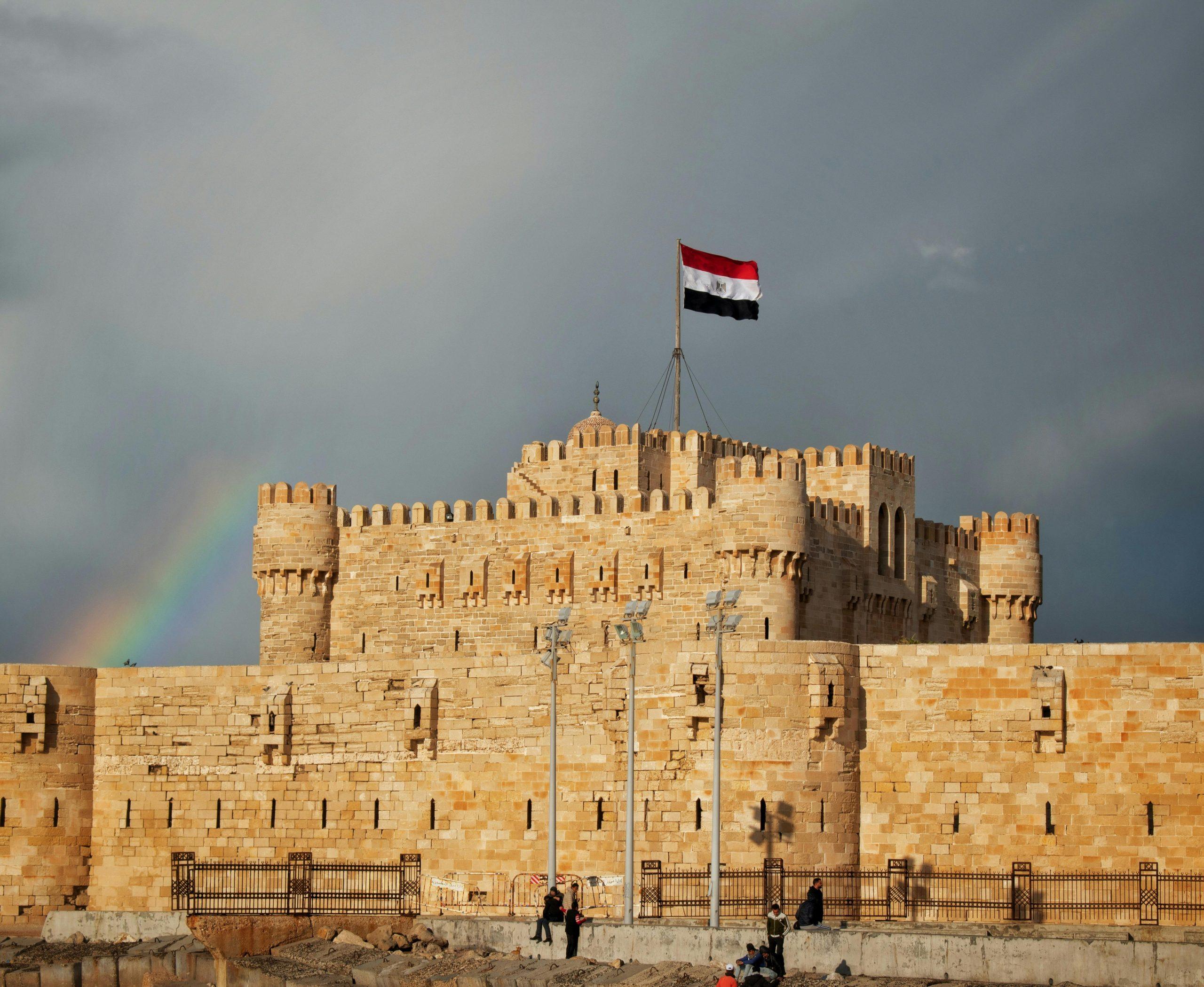 Qaitbay Citadel in Alexandria, Egypt at sunset showing stone walls, towers, and Mediterranean coastline