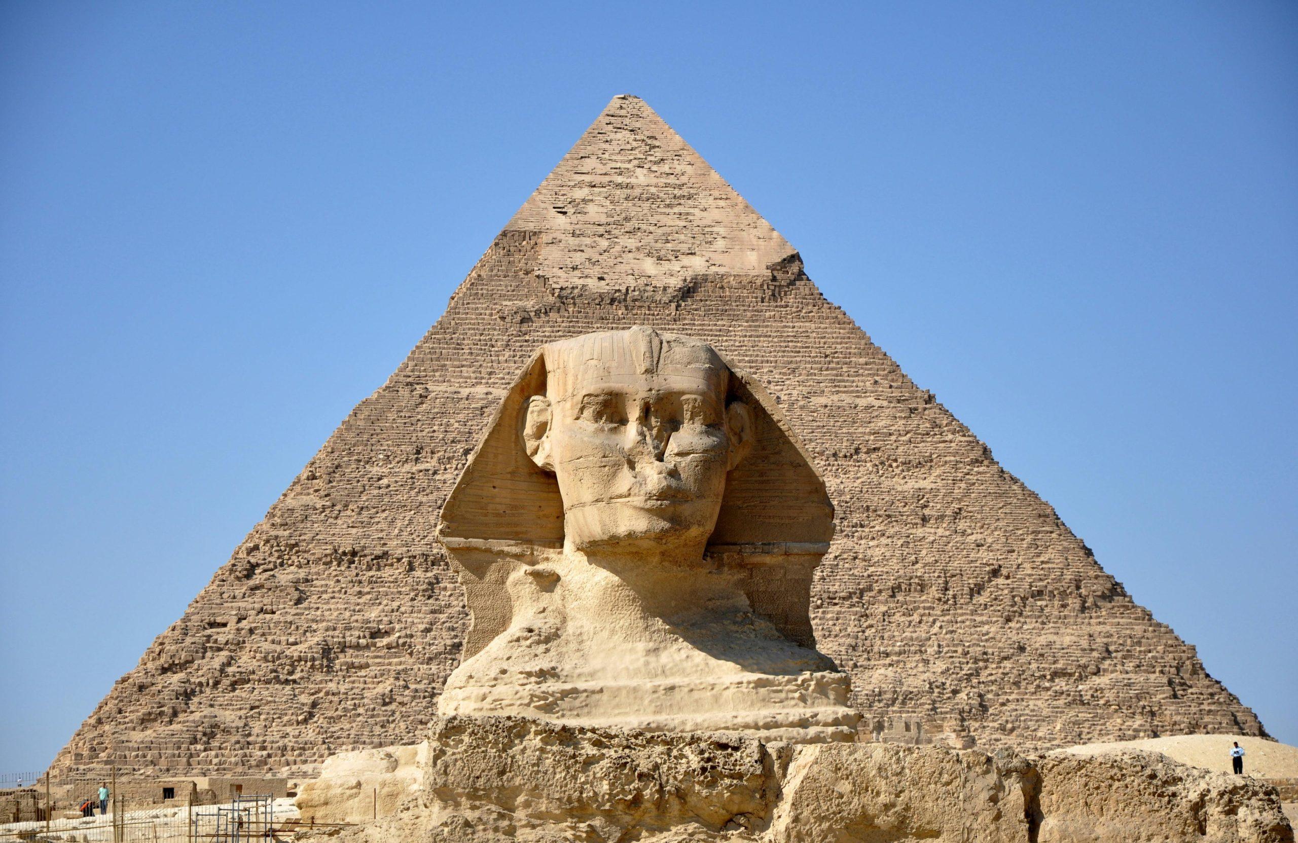 The three Great Pyramids of Giza standing in the Egyptian desert under a clear blue sky.
