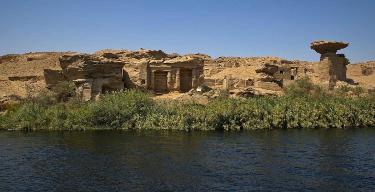 Panoramic view of the sandstone cliffs and rock-cut shrines at Gebel El Silsila along the Nile River in Egypt.