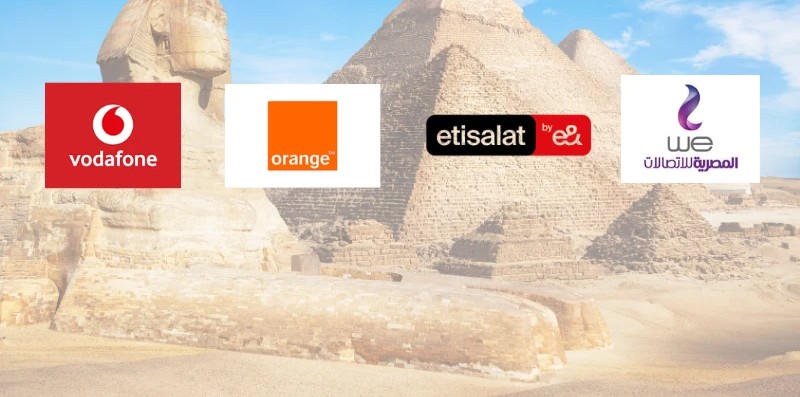Tourist holding a smartphone with an eSIM and Egyptian mobile SIM cards in front of the Pyramids